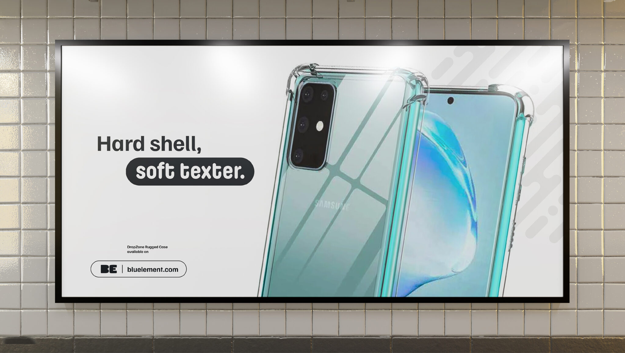 Une publicité sur panneau d'affichage montre deux smartphones équipés de coques transparentes. Le texte indique : « Coque rigide, SMS tout en douceur ». Dans le coin inférieur gauche, le logo de la marque BlueAnt et l'adresse de son site web apparaissent sur un fond représentant un mur carrelé blanc.