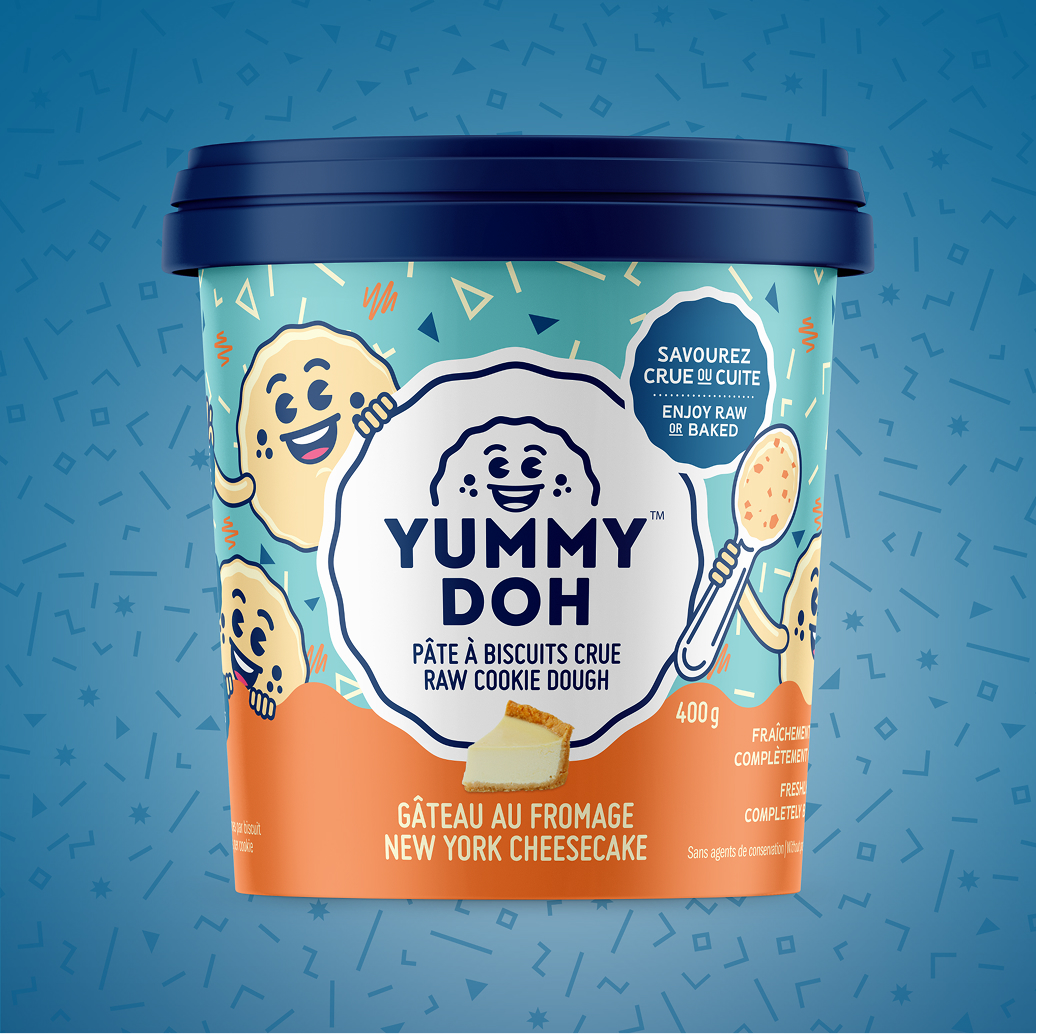 Un pot coloré de pâte à cookies crue « Yummy Doh », saveur cheesecake new-yorkais. L'emballage représente des personnages souriants en forme de cookies et de cuillères sur un fond bleu et orange, agrémenté de motifs ludiques de confettis.