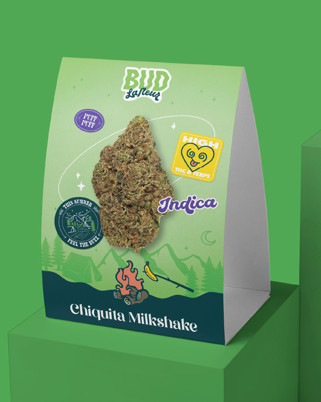 Un emballage de produit portant la mention « Bud Bakery » présente un gros bourgeon de cannabis, des illustrations colorées et des inscriptions telles que « Indica » et « Chiquita Milkshake », ainsi que divers autocollants ludiques sur fond vert.