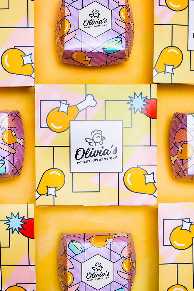 Un emballage coloré arborant le logo « Olivia’s Authentic Chicken » sur les boîtes et les emballages, avec des pilons et des ailes de poulet dessinés ainsi que des formes géométriques sur un fond jaune et violet.