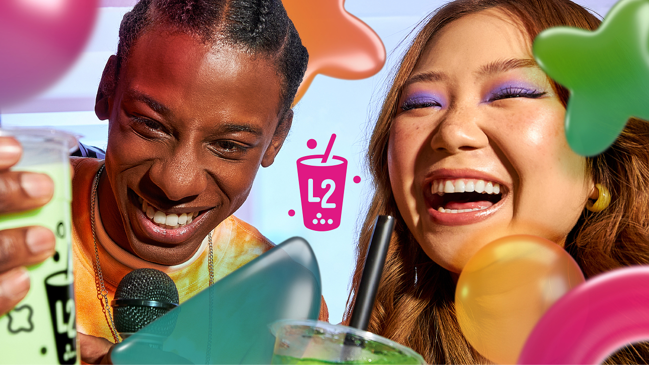 Deux personnes souriantes tenant des gobelets L2 Bubble Tea et riant, entourées de ballons colorés, avec le logo L2 Bubble Tea au centre de l'image.