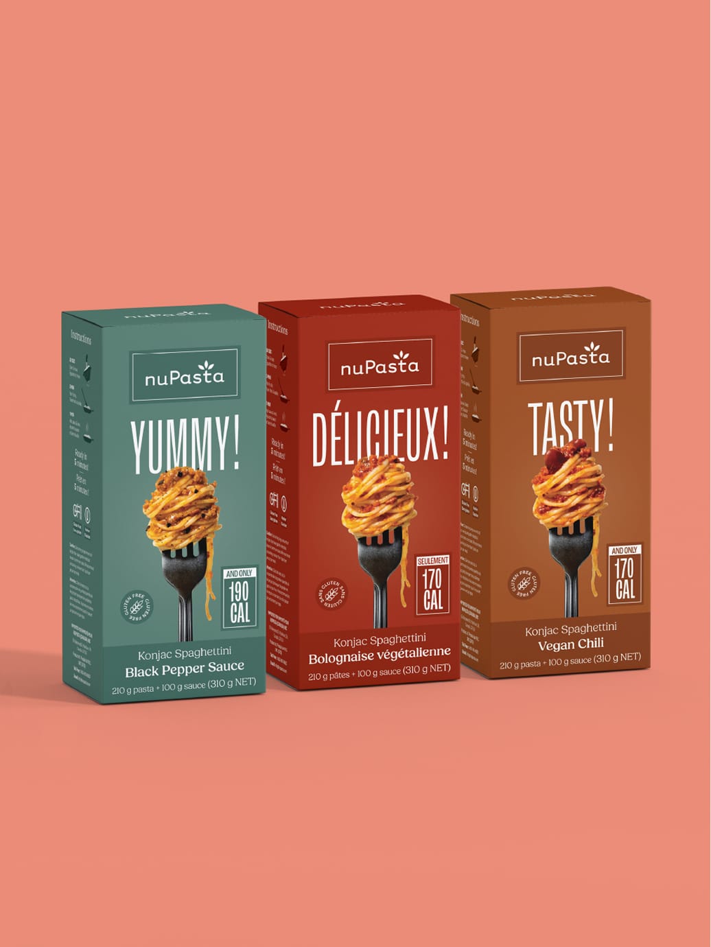 Trois boîtes de spaghettis nuPasta au konjac, disponibles en différentes saveurs — sauce au poivre noir, bolognaise et chili végétalien — sont présentées debout sur un fond rose ; chacune arbore sur le devant une fourchette avec des spaghettis.