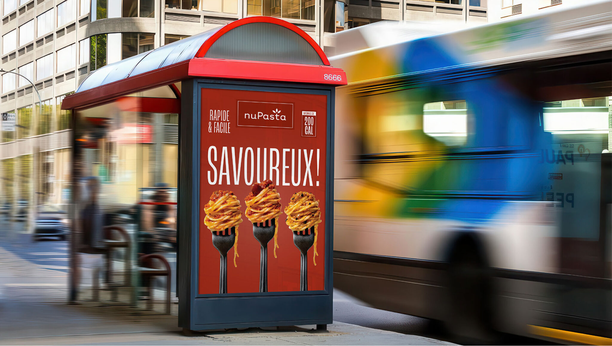 Une publicité sur un abribus représentant trois fourchettes piquant des pâtes sur fond rouge, avec le texte « SAVOUREUX ! » et faisant la promotion d'une marque appelée nuPasta. Un bus flou passe dans une rue de la ville.