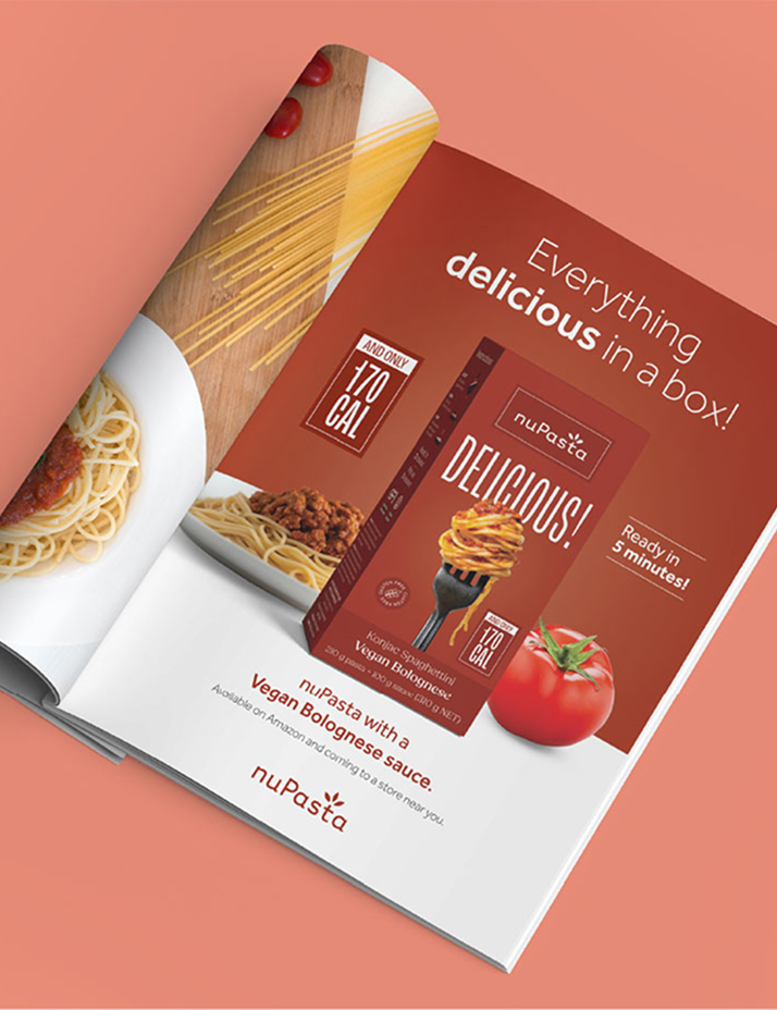 Le magazine Open présente une publicité pour NuPasta montrant une boîte de pâtes, des tomates et des spaghettis cuits. Le texte met en avant le slogan « Tout ce qu’il y a de délicieux dans une boîte ! » et mentionne une sauce bolognaise végane, 170 calories et un temps de préparation de 5 minutes.
