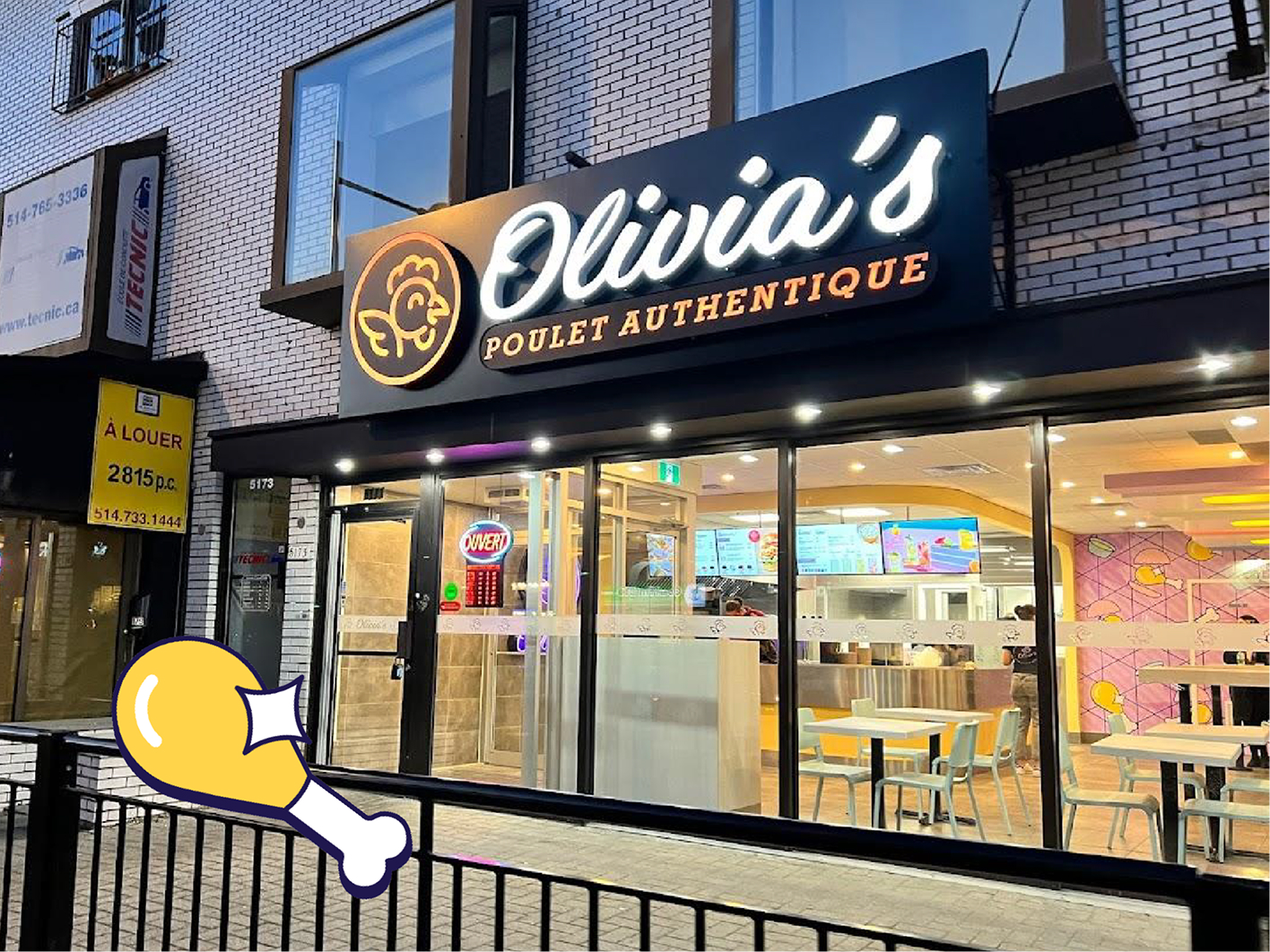 Vue extérieure du restaurant « Olivia’s Poulet Authentique », spécialisé dans le poulet authentique, de nuit : enseigne lumineuse, grandes baies vitrées laissant entrevoir les tables et les écrans affichant les menus à l’intérieur, avec l’image d’un pilon de poulet dans le coin inférieur gauche.