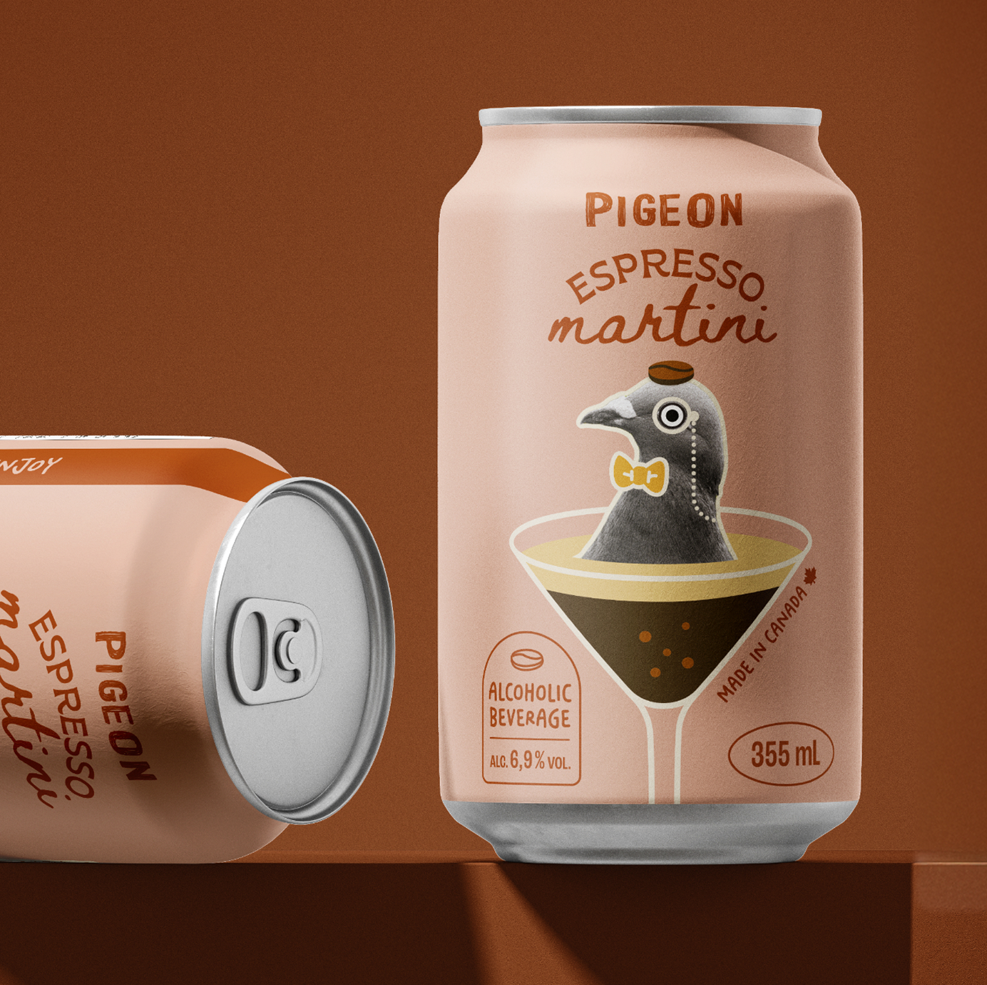 On voit deux canettes de la boisson alcoolisée « Pigeon Espresso Martini », l'une debout et l'autre couchée. La canette debout est ornée d'une illustration représentant un pigeon dans un verre à martini, portant un nœud papillon.